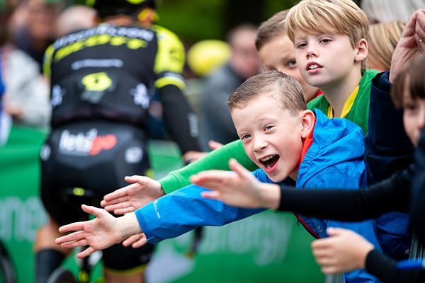 Children waving on the cyclists