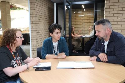 Three people in an meeting sat at a desk